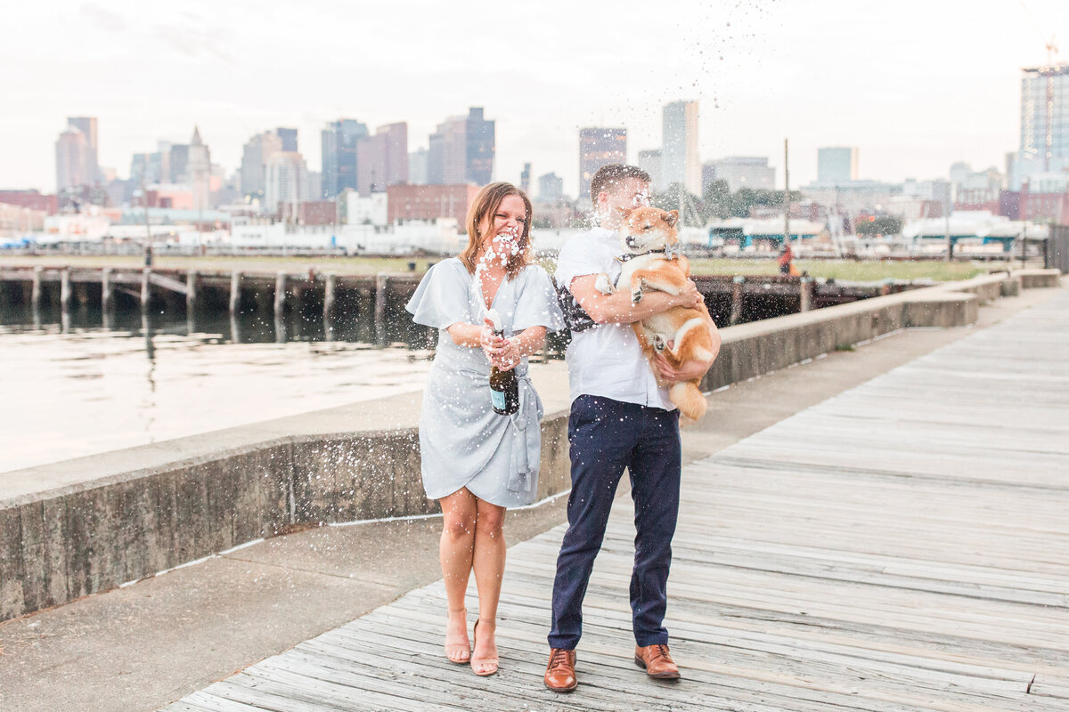 couple holding their dog and popping champagne in Charlestown Navy Yard