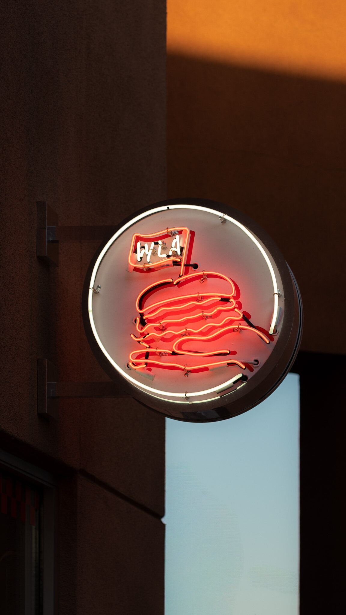 Illuminated neon burger sign with “WLA” flag outside With Love, Always restaurant in Las Vegas
