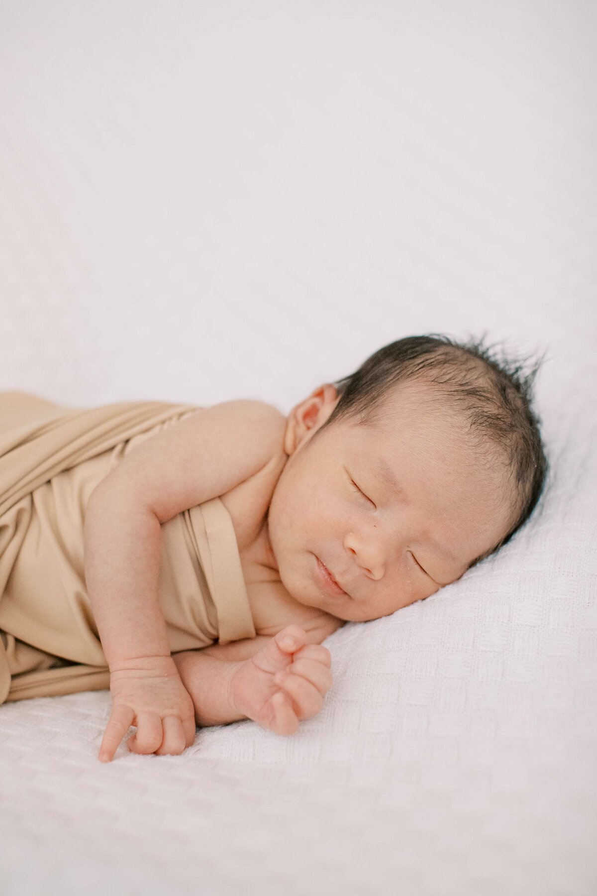 newborn baby boy wrapped in a neutral-colored swaddle