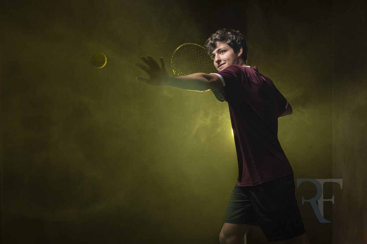 Photographer in Avon | Rob Faber Photography | Studio portrait of tennis player with dark background and yellow smoke hitting a tennis ball.