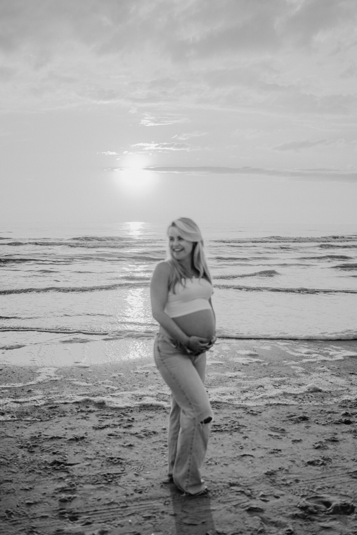 Zwangere vrouw houdt buik vast tijdens zwangersschapsshoot in de Soesterduinen.