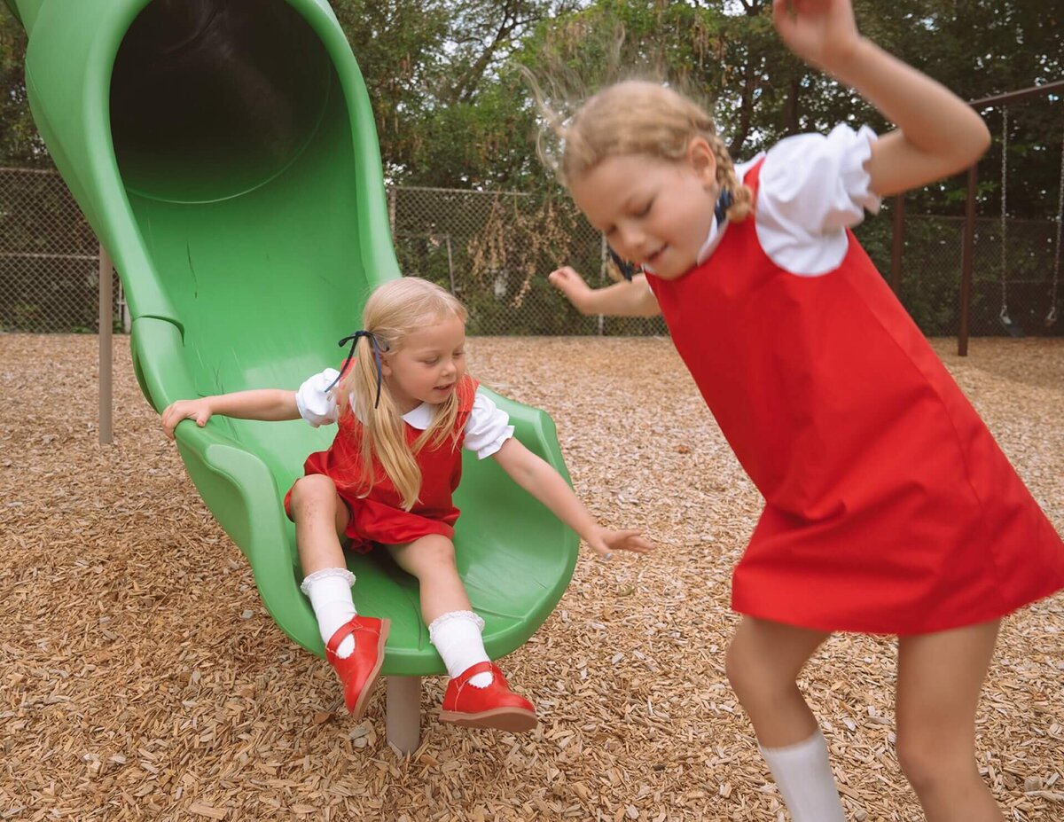 two little girls playing on green slide