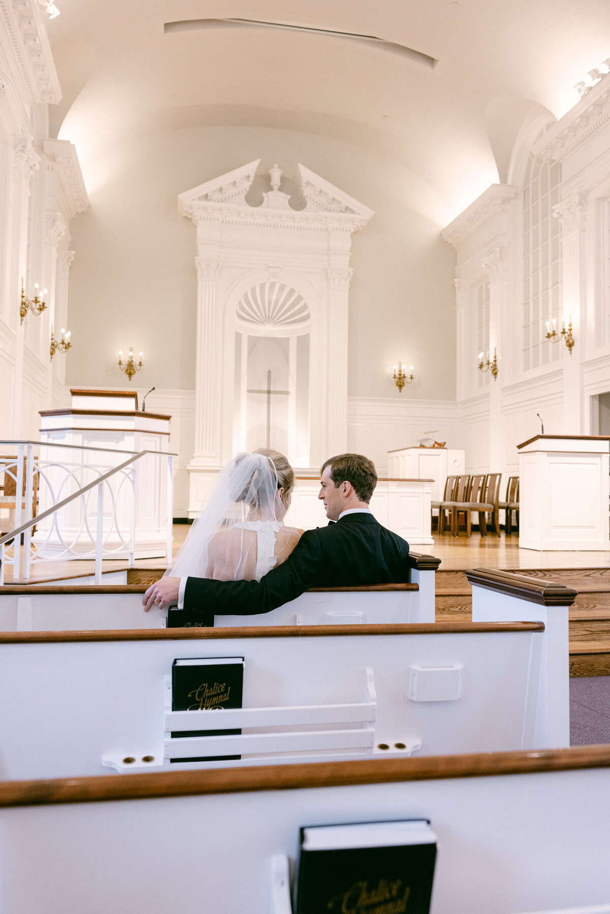 A wedding day photo of the bride and groom sitting in the church after their ceremony
