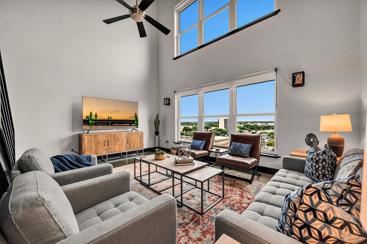 Living room with ample seating in this 2 bedroom, 2.5 bathroom top floor vacation rental condo in historic Behrens building with views of the Brazos River and McLane Stadium in downtown Waco, TX