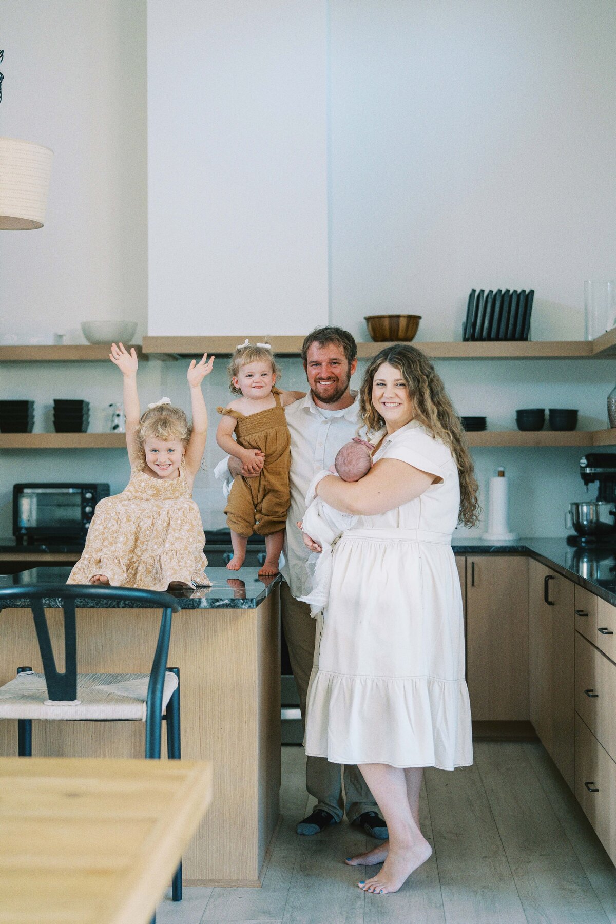 family smiling at camera while standing in their kitchen
