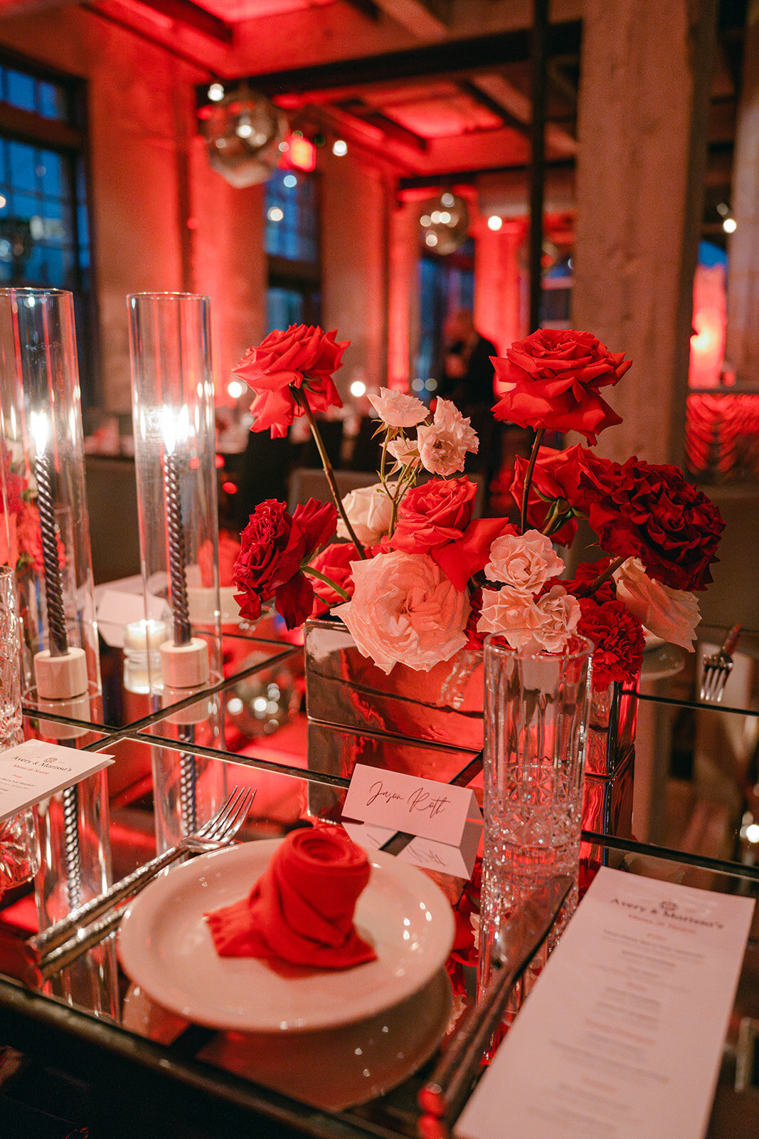 Bold red floral arrangement styled with flickering candlelight in upscale San Antonio reception