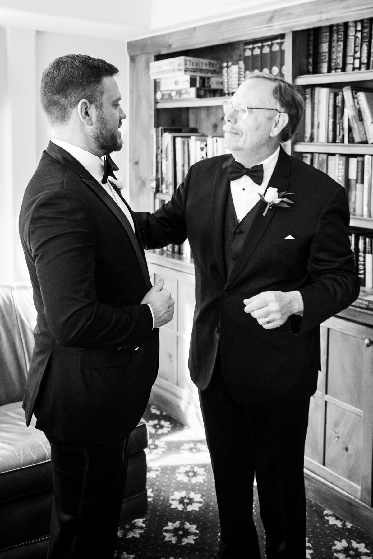 A candid shot of a groom and his father looking at each other as they get ready on his wedding day.