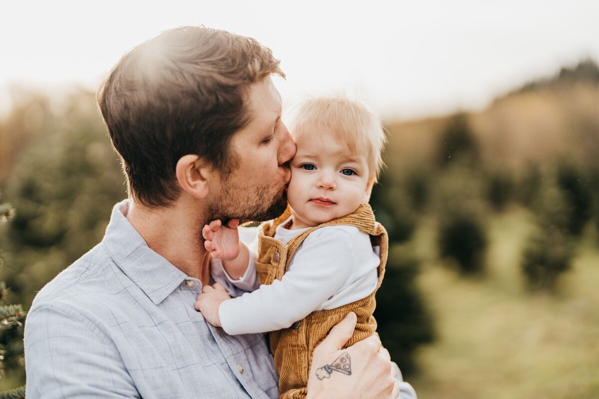 dad-kissing-his-son-in-golden-light-at-tree-farm