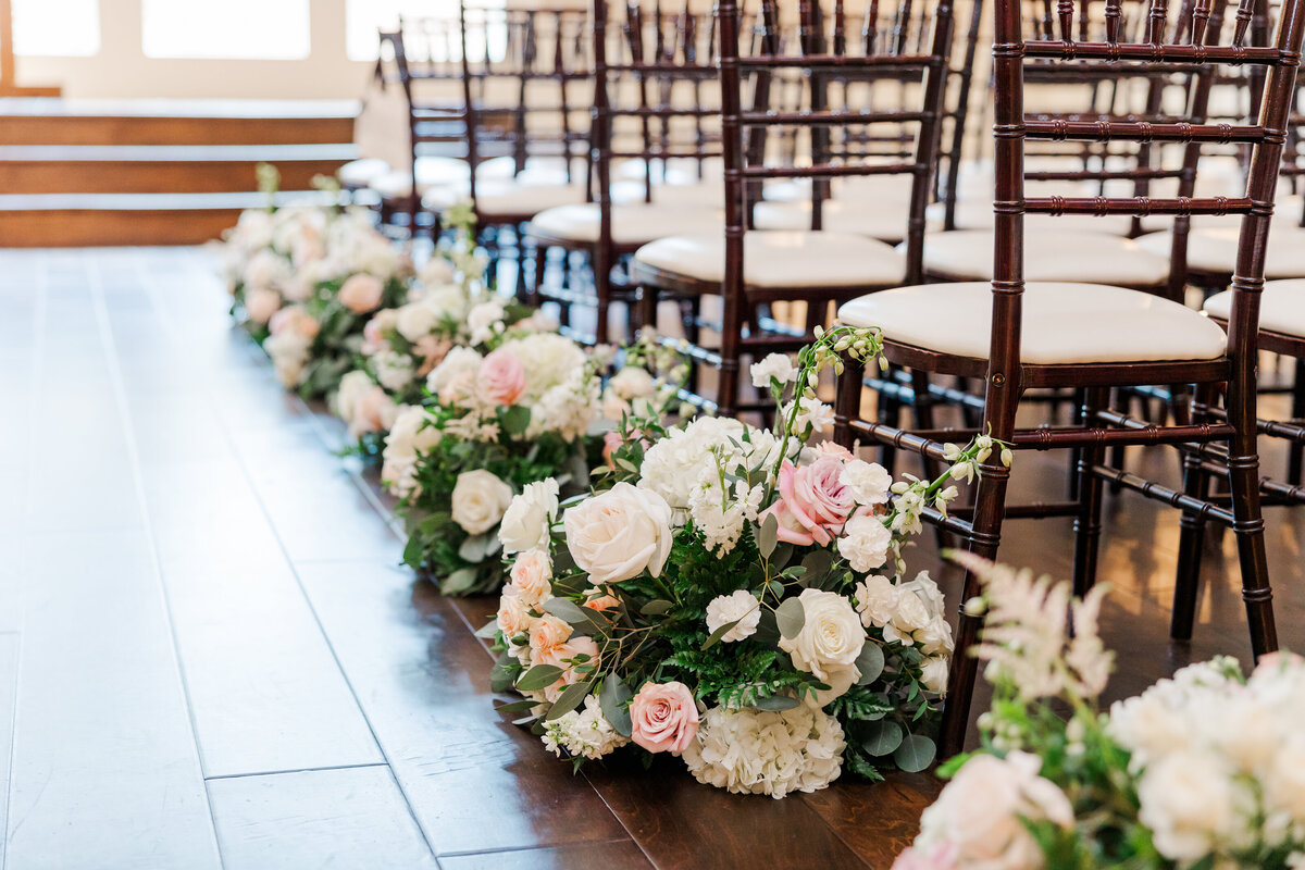 Elegant rows of white and blush garden roses line the ceremony aisle at a classic Southern wedding near Aubrey, TX. A soft, floral design filled with hydrangeas and greenery creates a graceful and timeless ambiance.