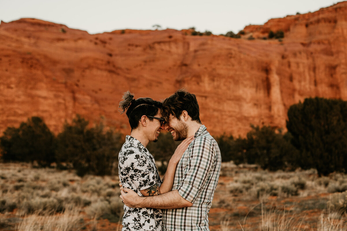 same sex couple in front of red rock in New Mexico