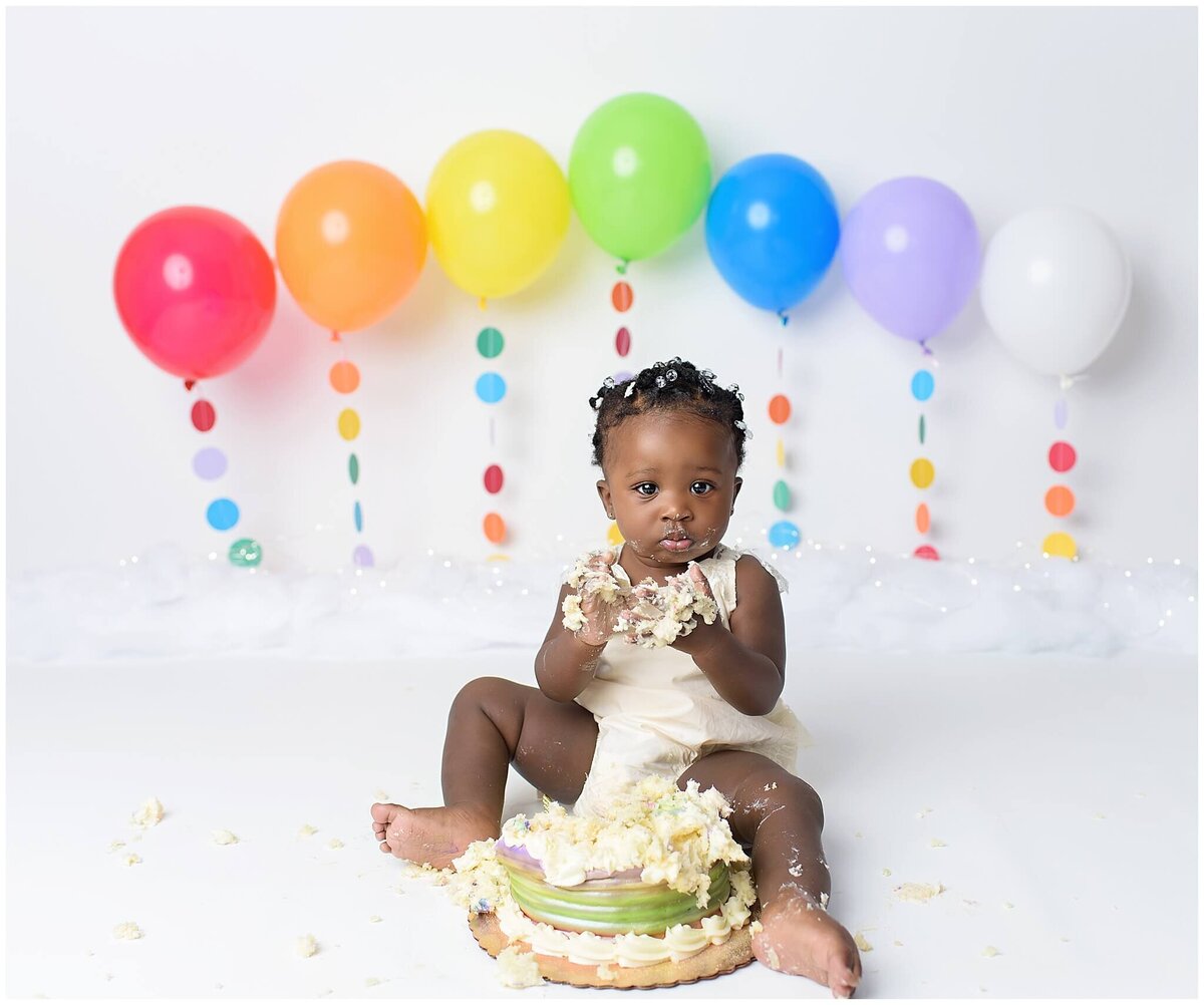 A sweet cake smash session capturing a girl's excitement and delight as she explores a cake.