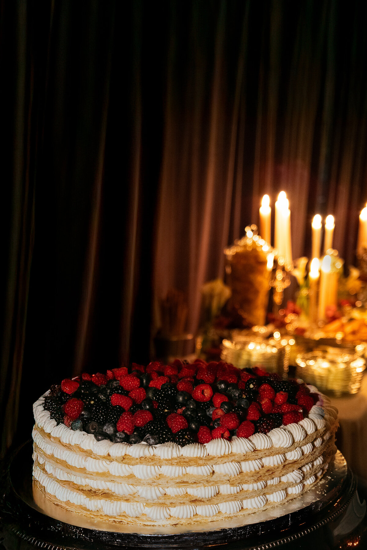 photographer takes photo of wedding cake with fruit at reception