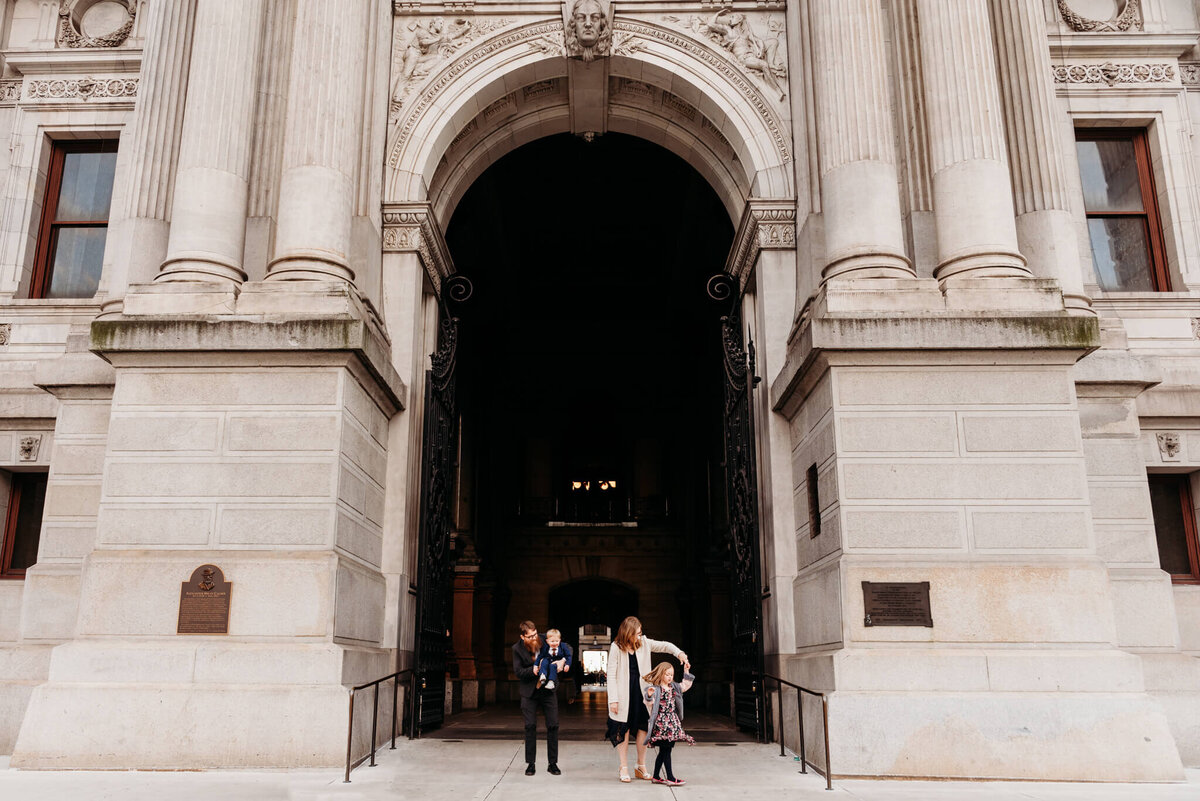 Family of four dancing in the archway of city hall during their Philadelphia family photography session