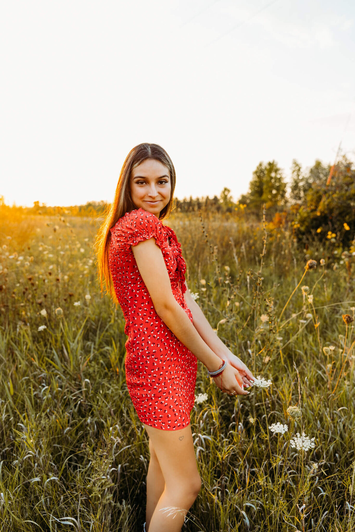 girl smiling in red dress at sunset for senior photography session
