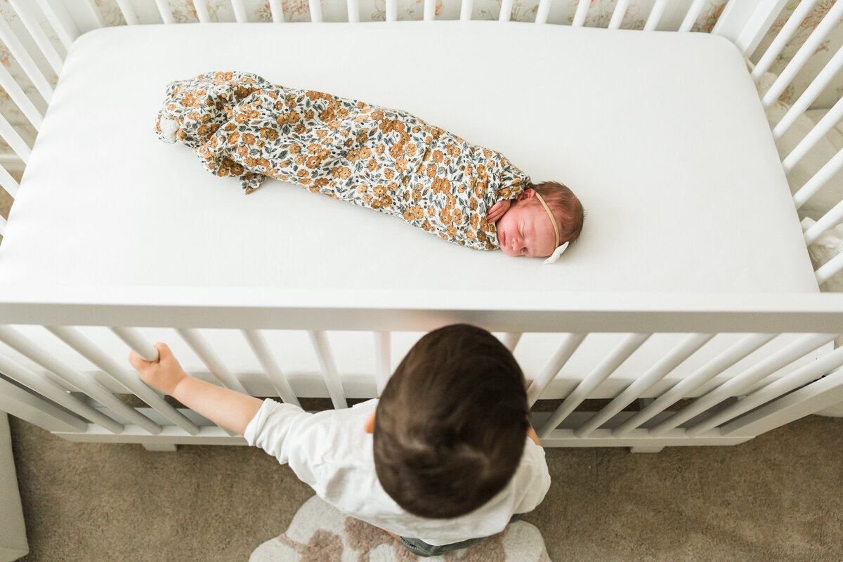 brother looking at newborn baby sister