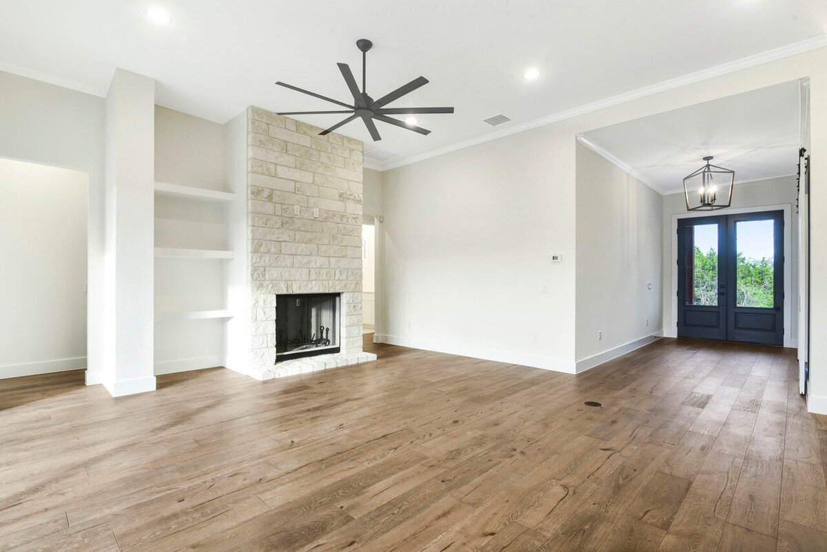 living room with limestone fireplace with big fan and black double doors at entry