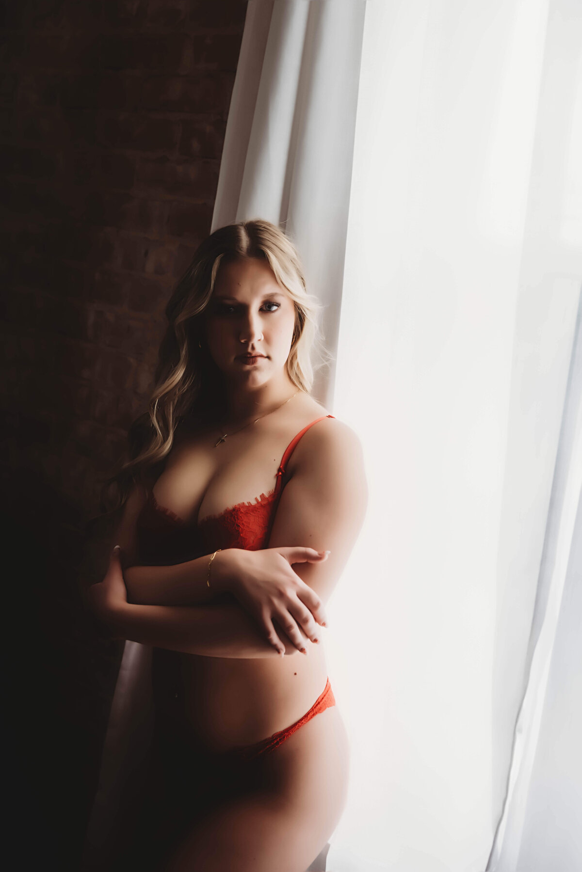 woman standing in window for boudoir session with reva davis photography