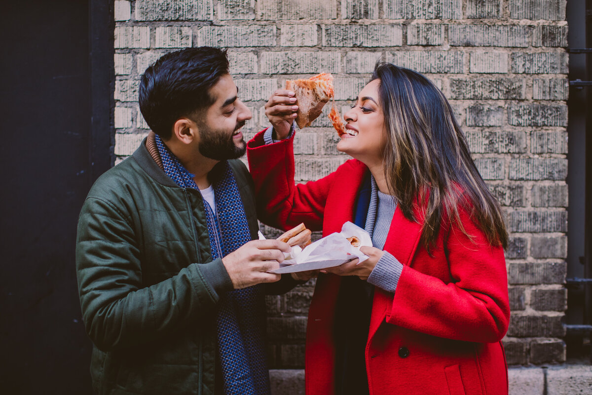 Engaged couple smiling and eating pizza outside in new york city 