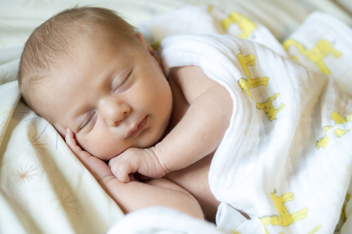 A newborn wrapped in a blanket sleeping 