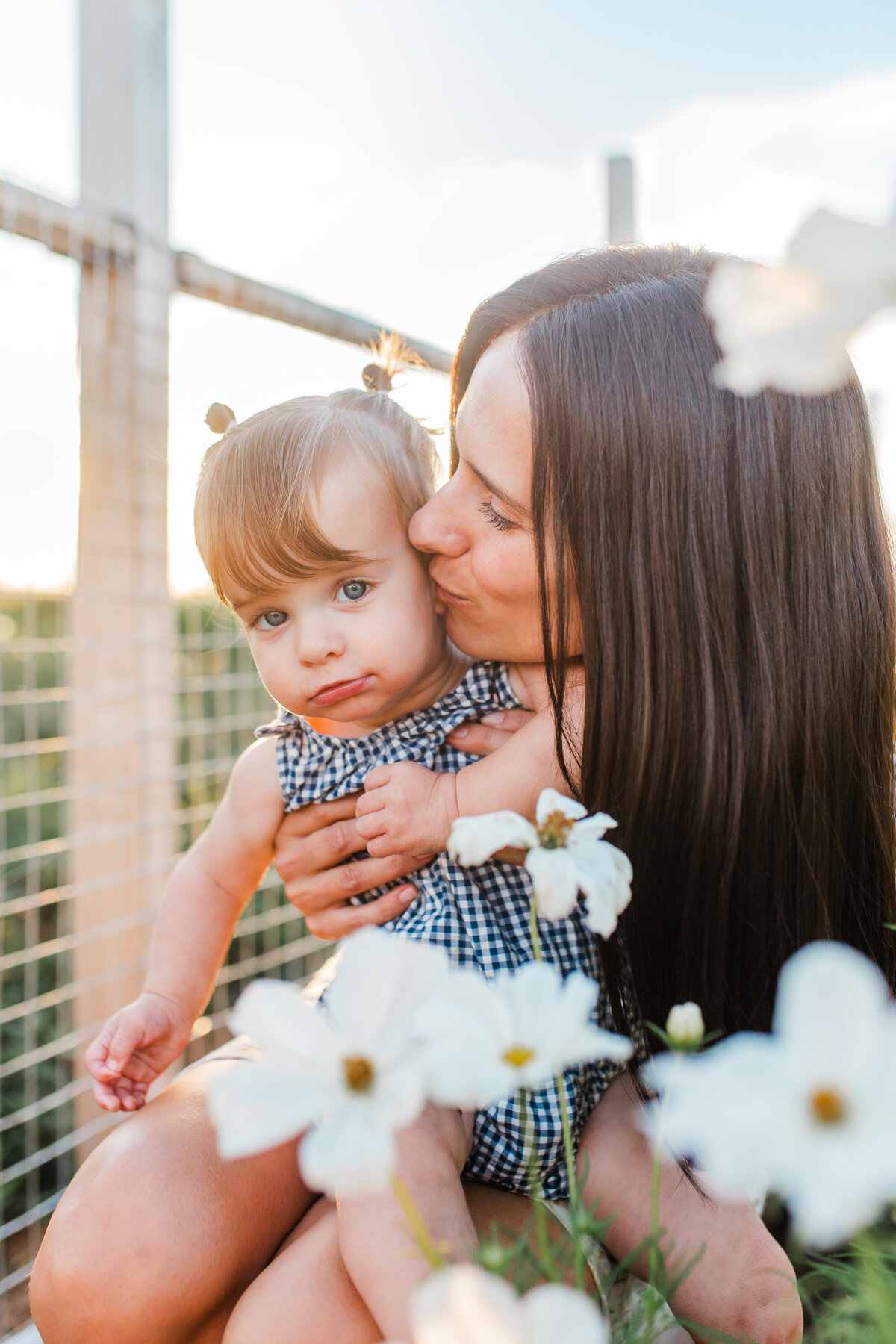 Mother kissing her toddler among white flowers
