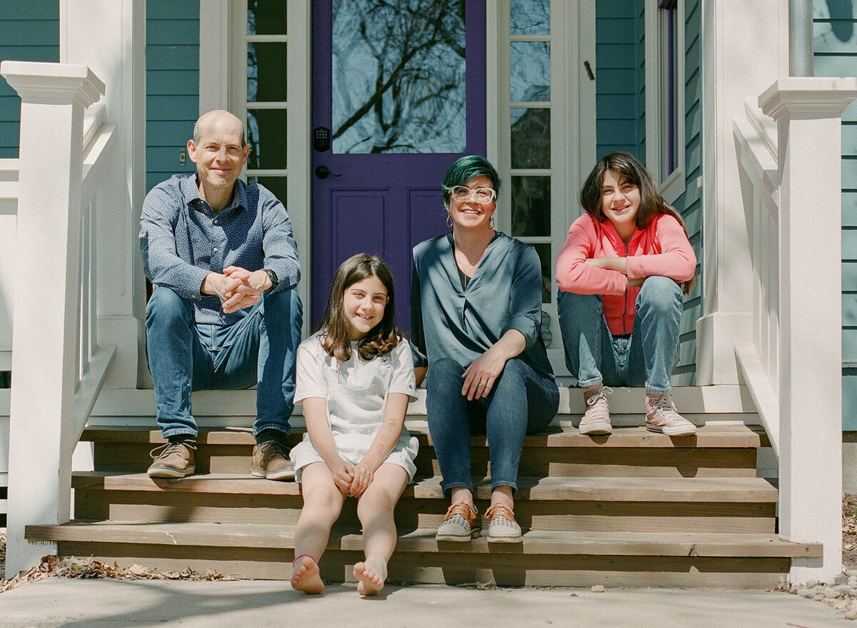 family sits on front porch for a professional photo