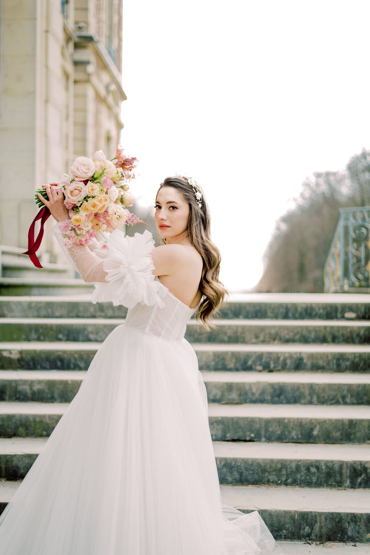 The bride is holding up her beautiful flowers in france at chateau de sceaux