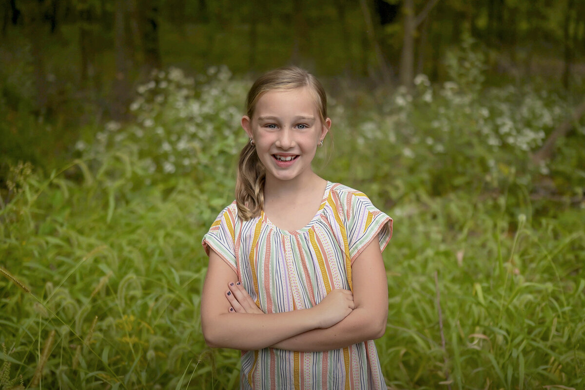 Girl wearing a striped top crosses her arms and smiles