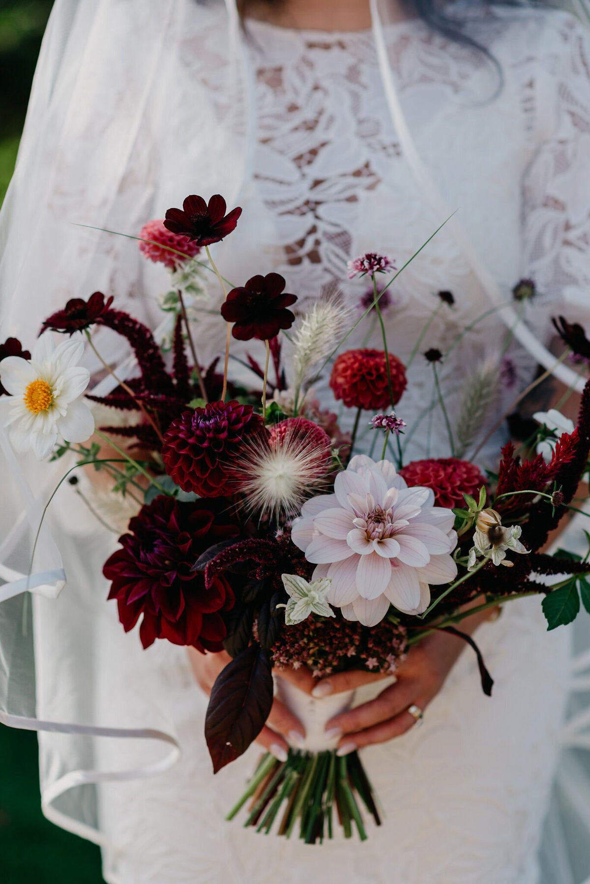 A bride holds an organic bouquet of dark flowers at a Montreal wedding.