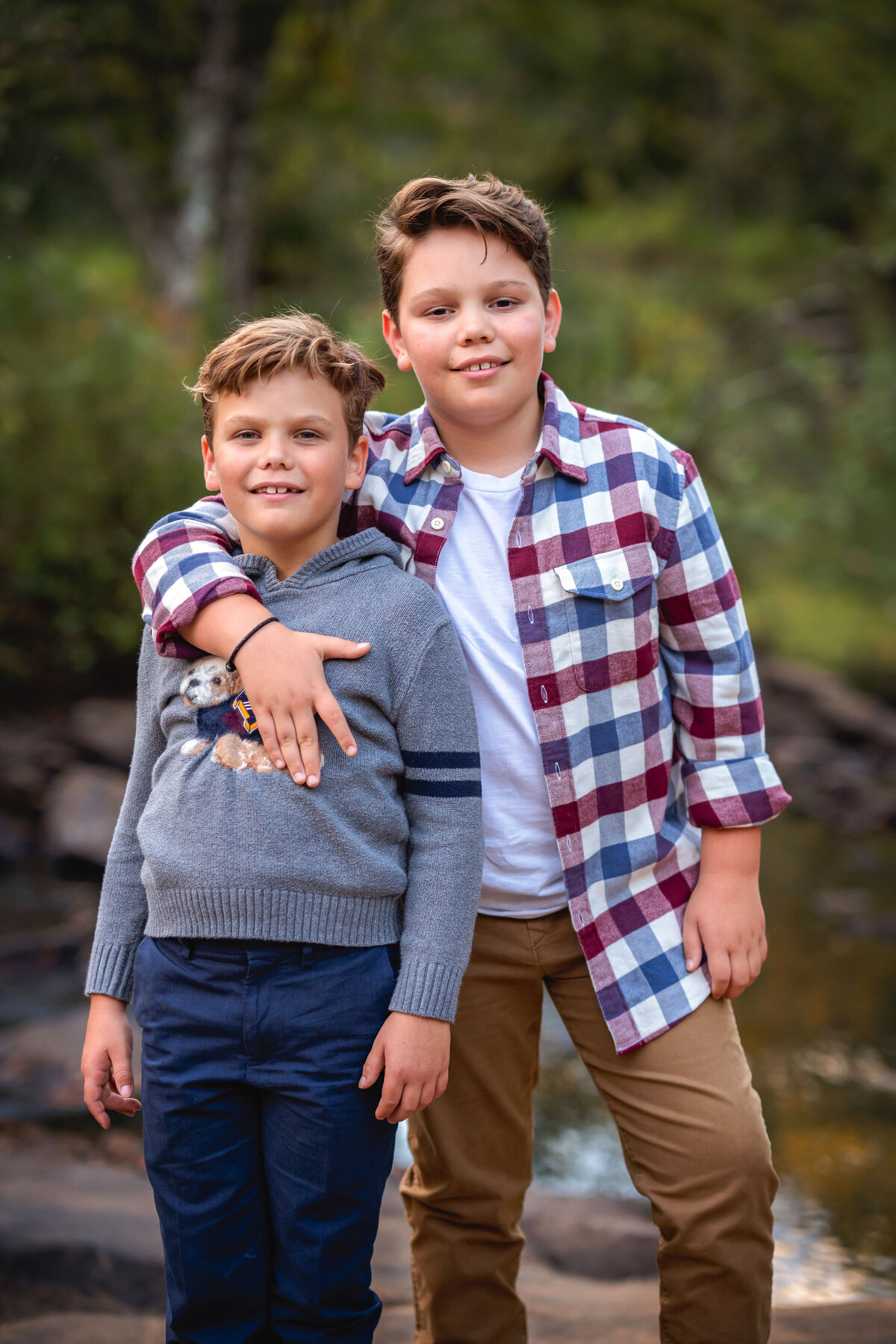 Two brothers embrace and smile for the camera during their family photography session.