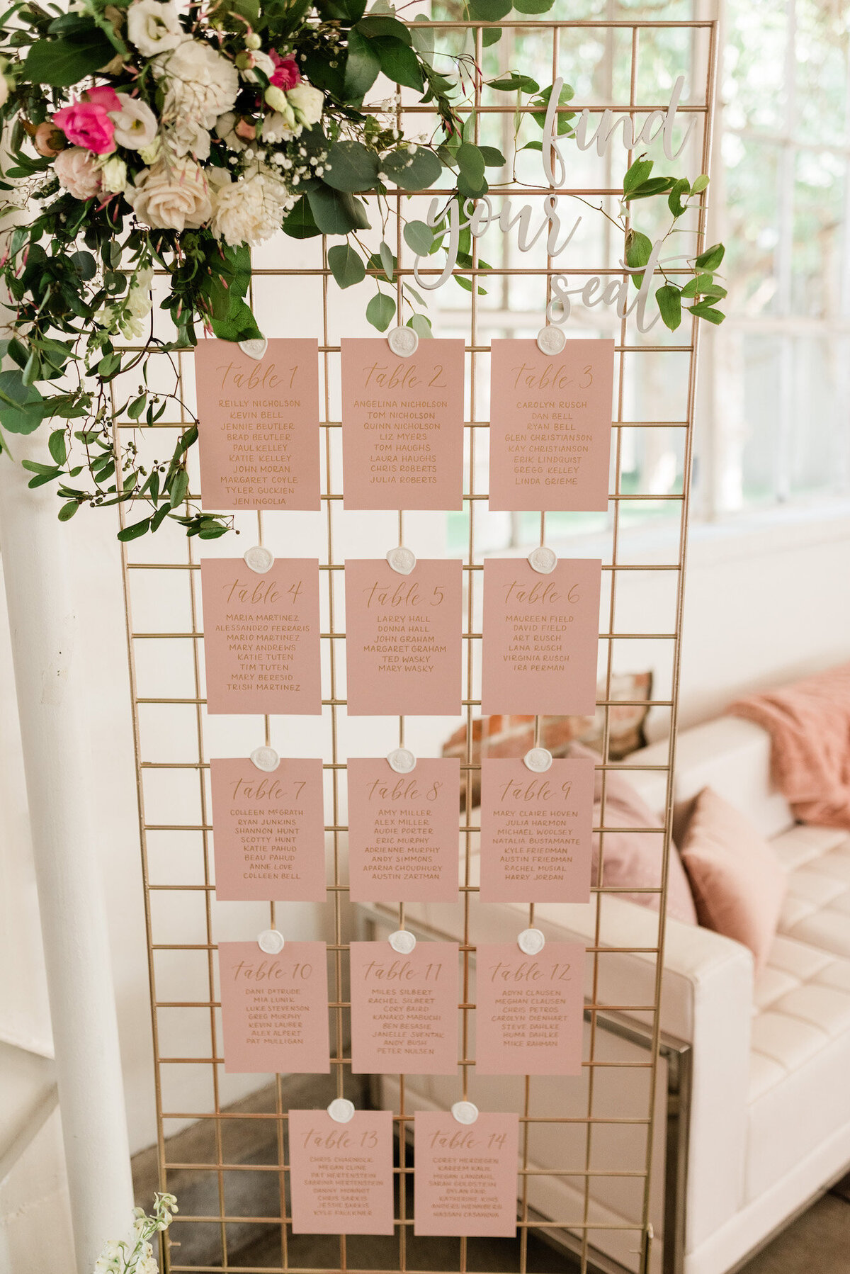 Dusty rose seating chart cards attached to a trellis for a wedding in Denver