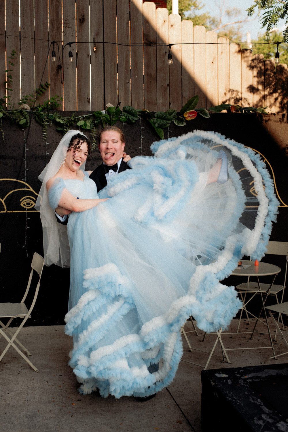 Groom lifts bride in front of brewery