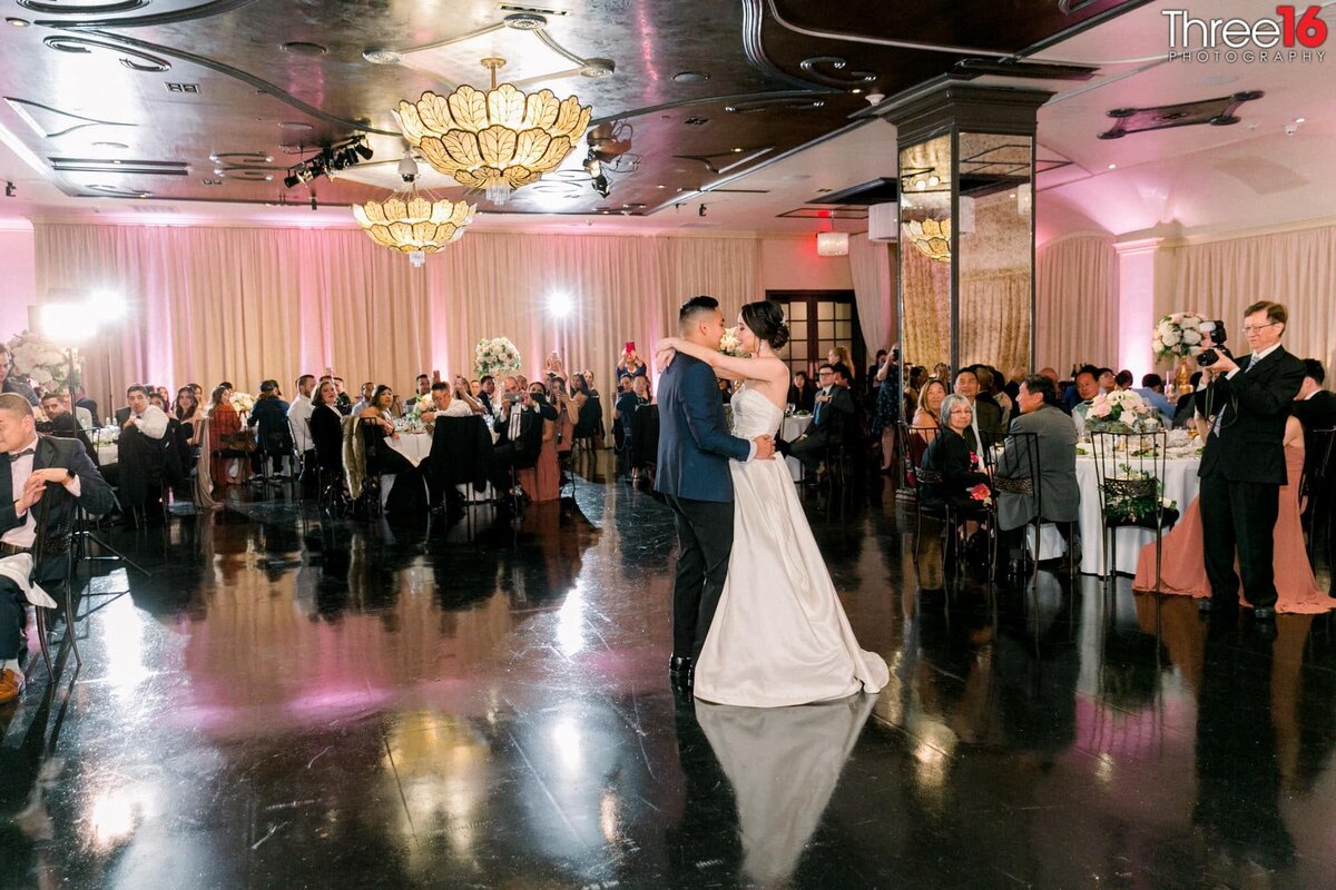 Bride and Groom share their first dance as guests look on