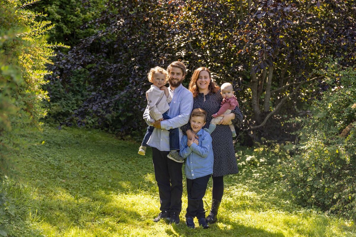 Familie på fem fotografert i en hage av Fotograf Linn Landmark.