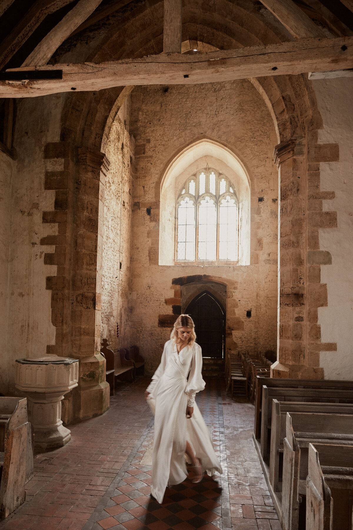 Bride wearing v-neck flowing silk wedding dress with long sleeves in church