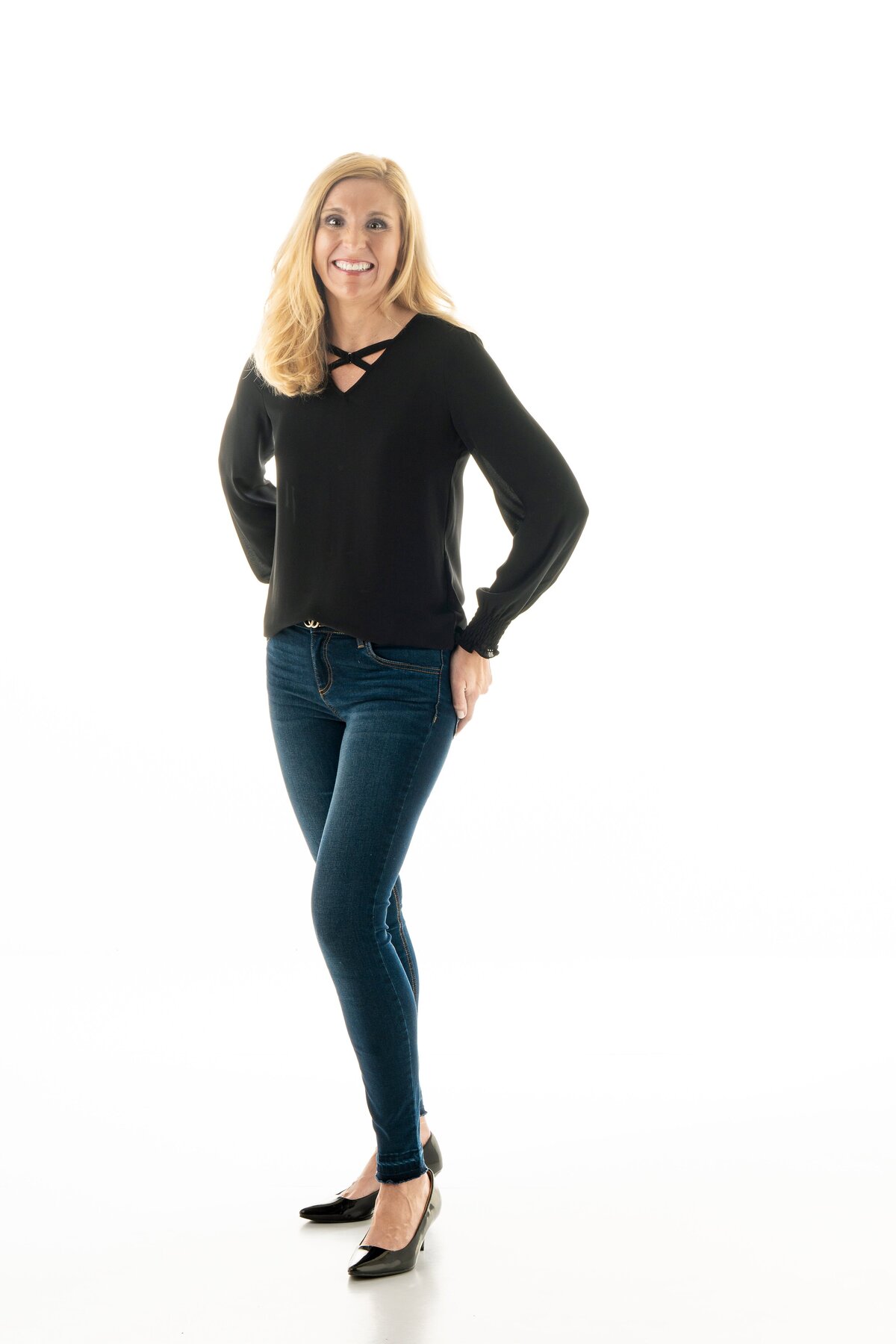 Professional woman in dressy black shirt, dress pants and heels on white background for branding and headshot.