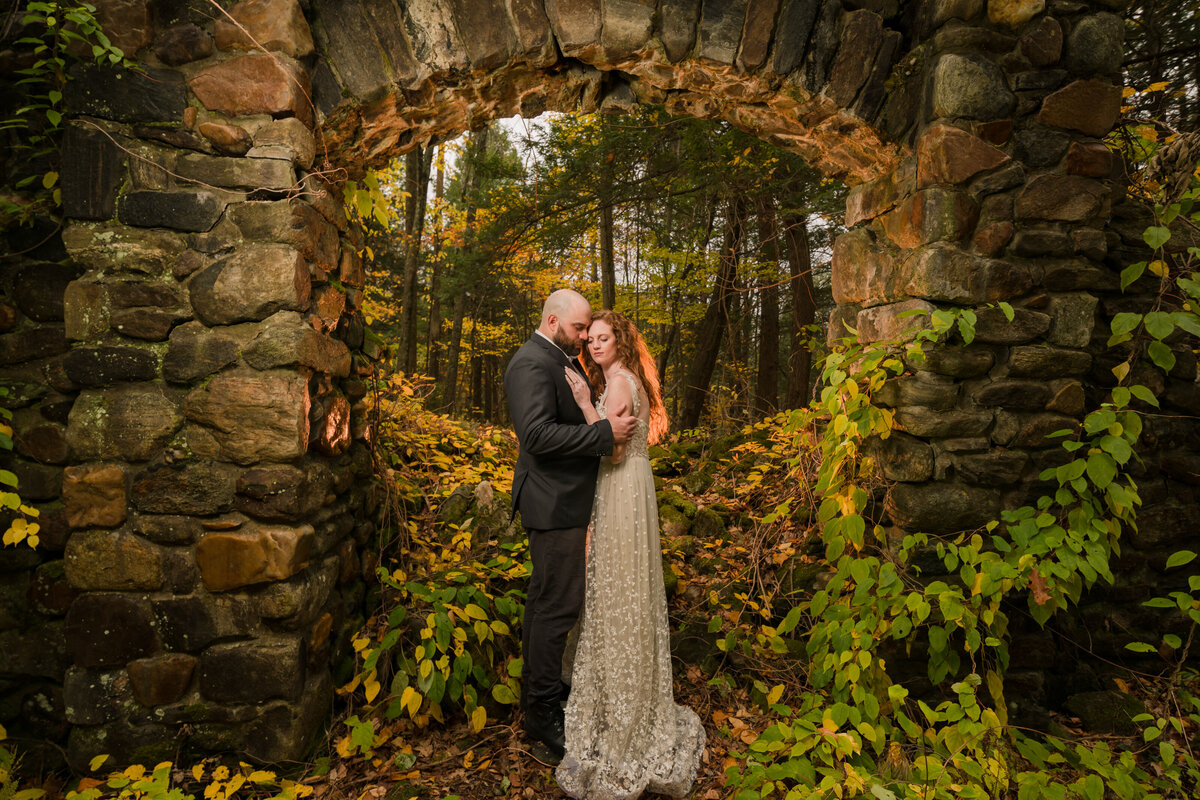bride and groom embracing under an arch in the mountains of MA