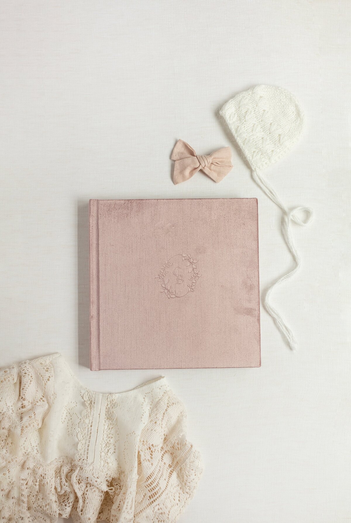 Pink leather album laid out with bow and bonnett