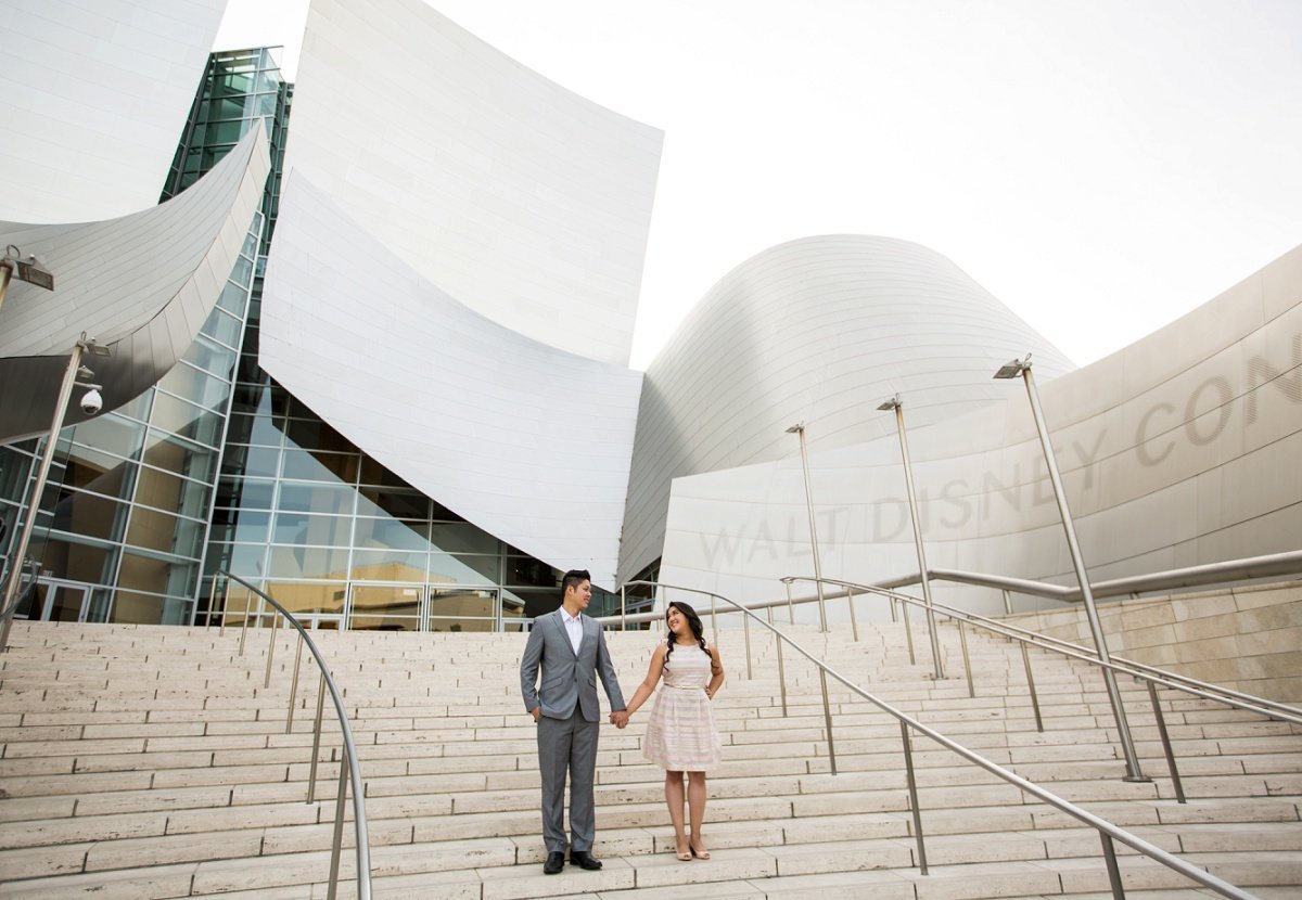 Engaged couple stare at each other while holding hands on the steps to the Walt Disney Concert Hall in LA