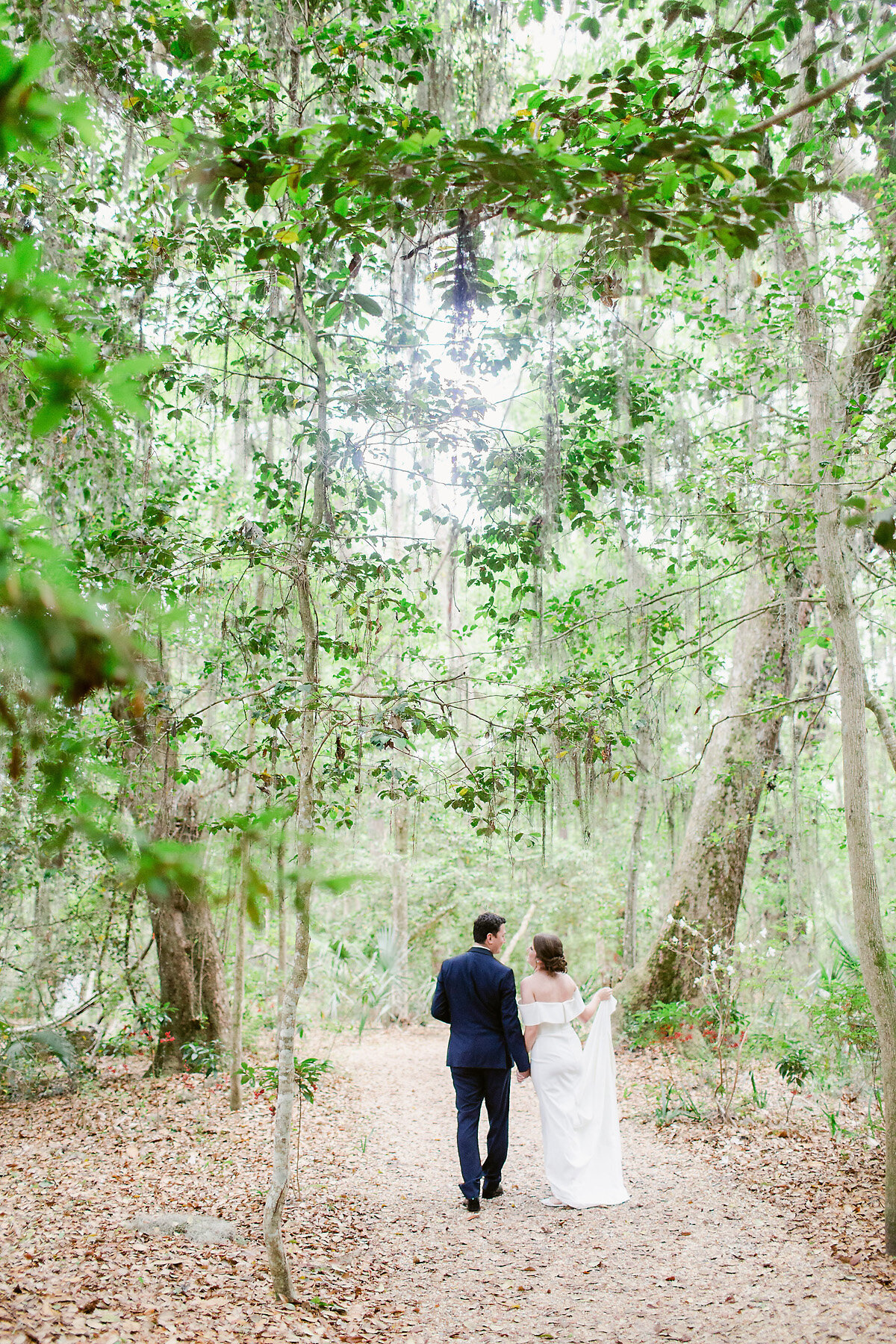Bride and groom walking through woods.
