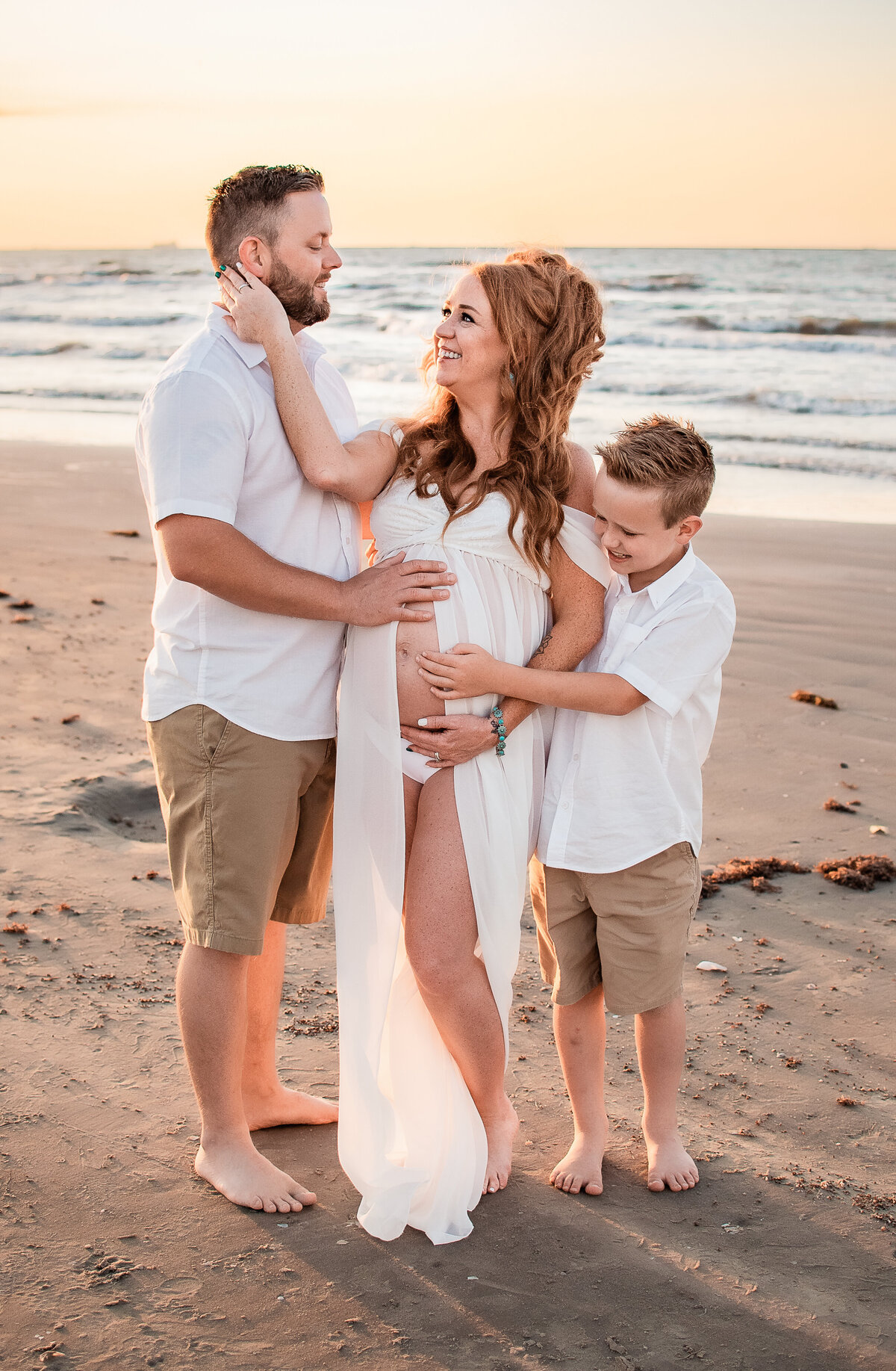 A Houston mom to be cuddles close with her husband and son at Beachtown in Galveston.