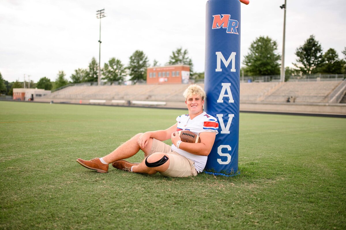 Marvin Rdige football player sits next to football uprights holding a football wearing his jersey