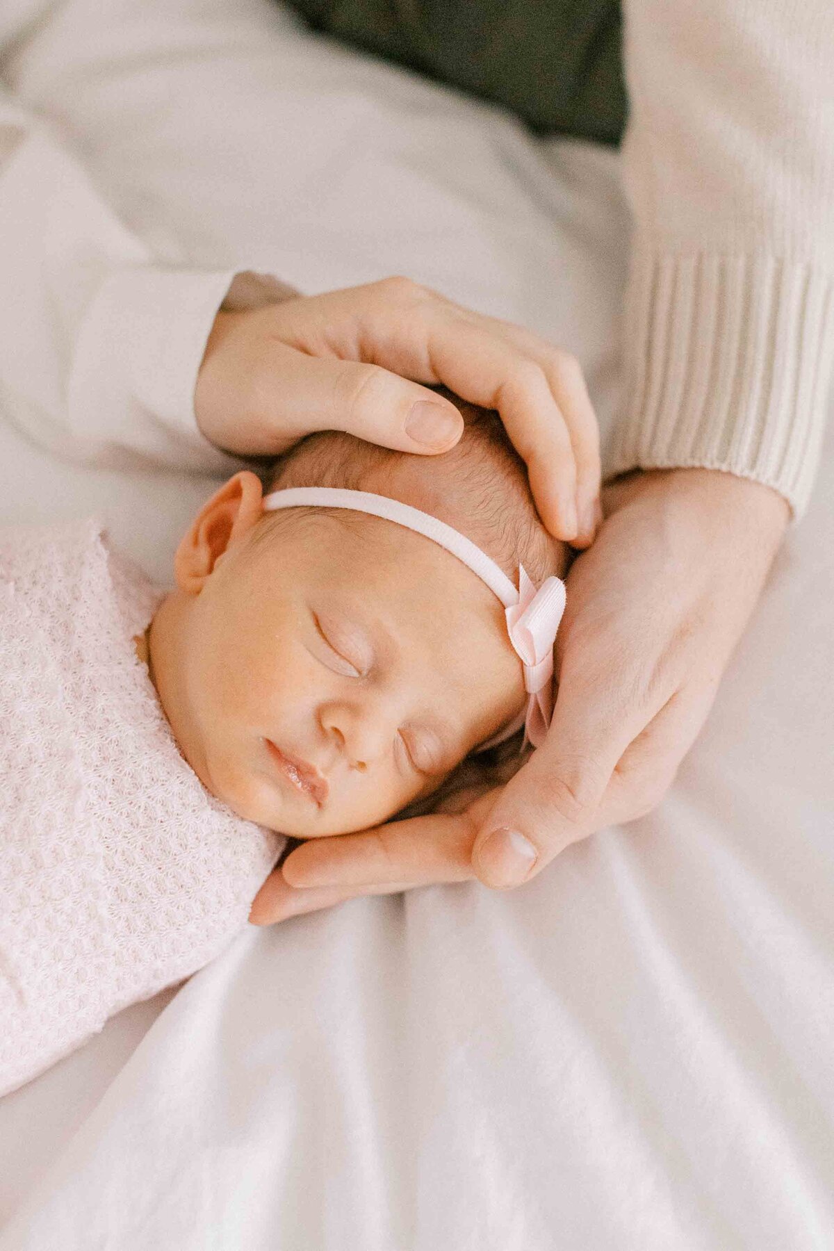 newborn baby girl being held by her parent's hands to show how tiny she is