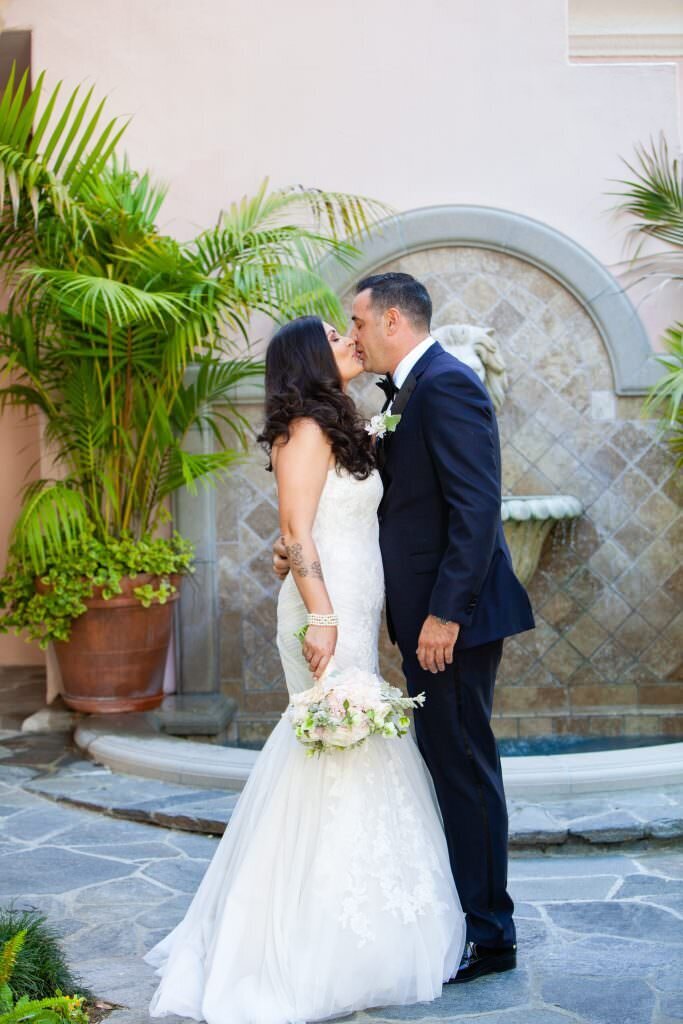 A bride and groom kissing while she holds a bouquet of flowers