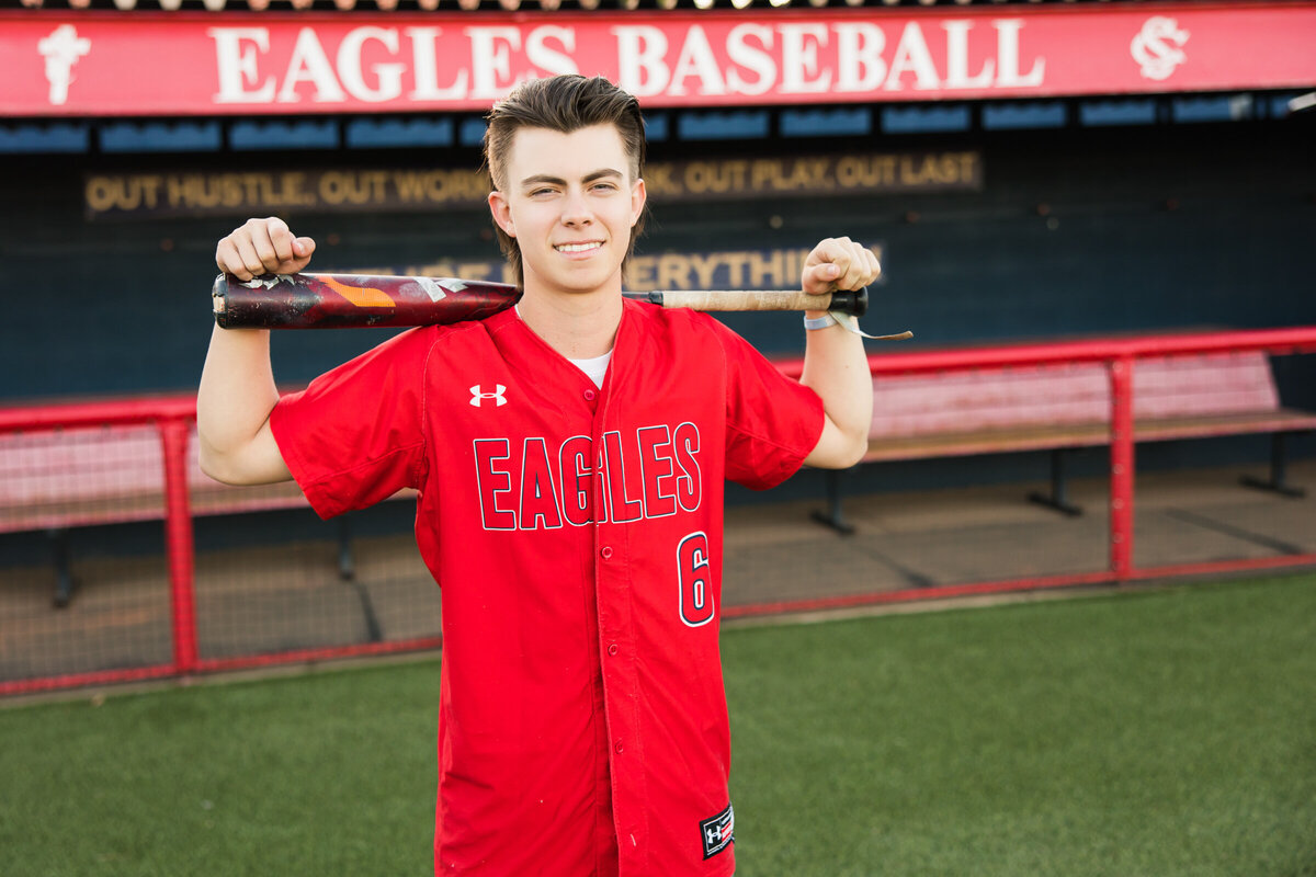 high school senior boy posing for Scottsdale senior photography session in baseball field