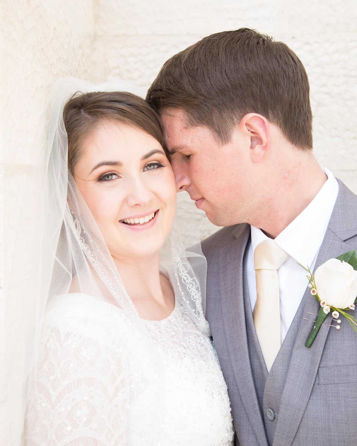 Beautiful bride and her groom leaning into her against a wall