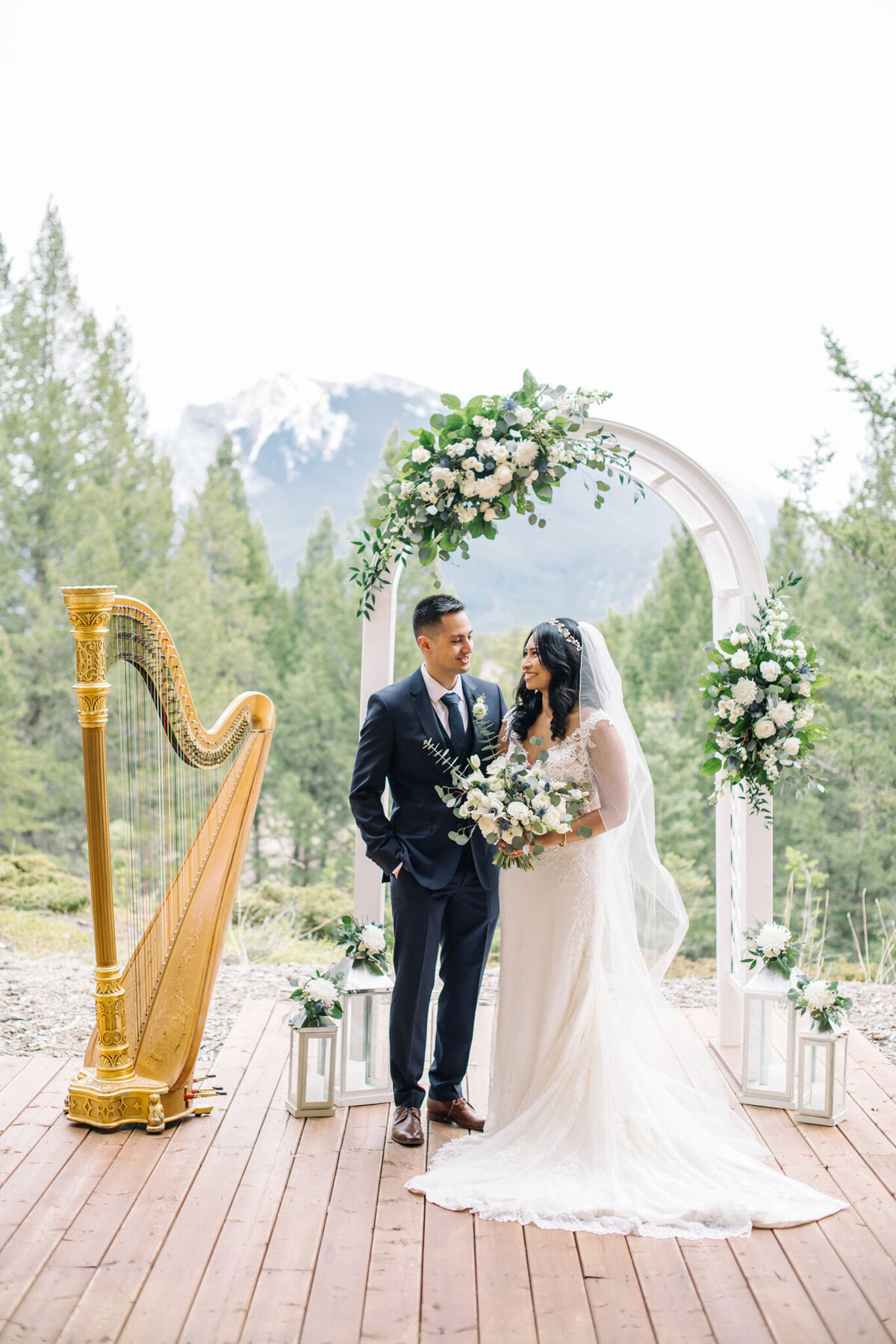 Couple in front of floral archway by Flower Aura By Natasha, classic Calgary, Alberta wedding florist, featured on the Brontë Bride Vendor Guide.