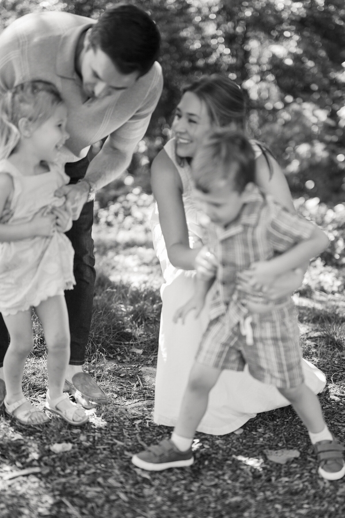 family with twins laughs while tickling them during family photos outdoors