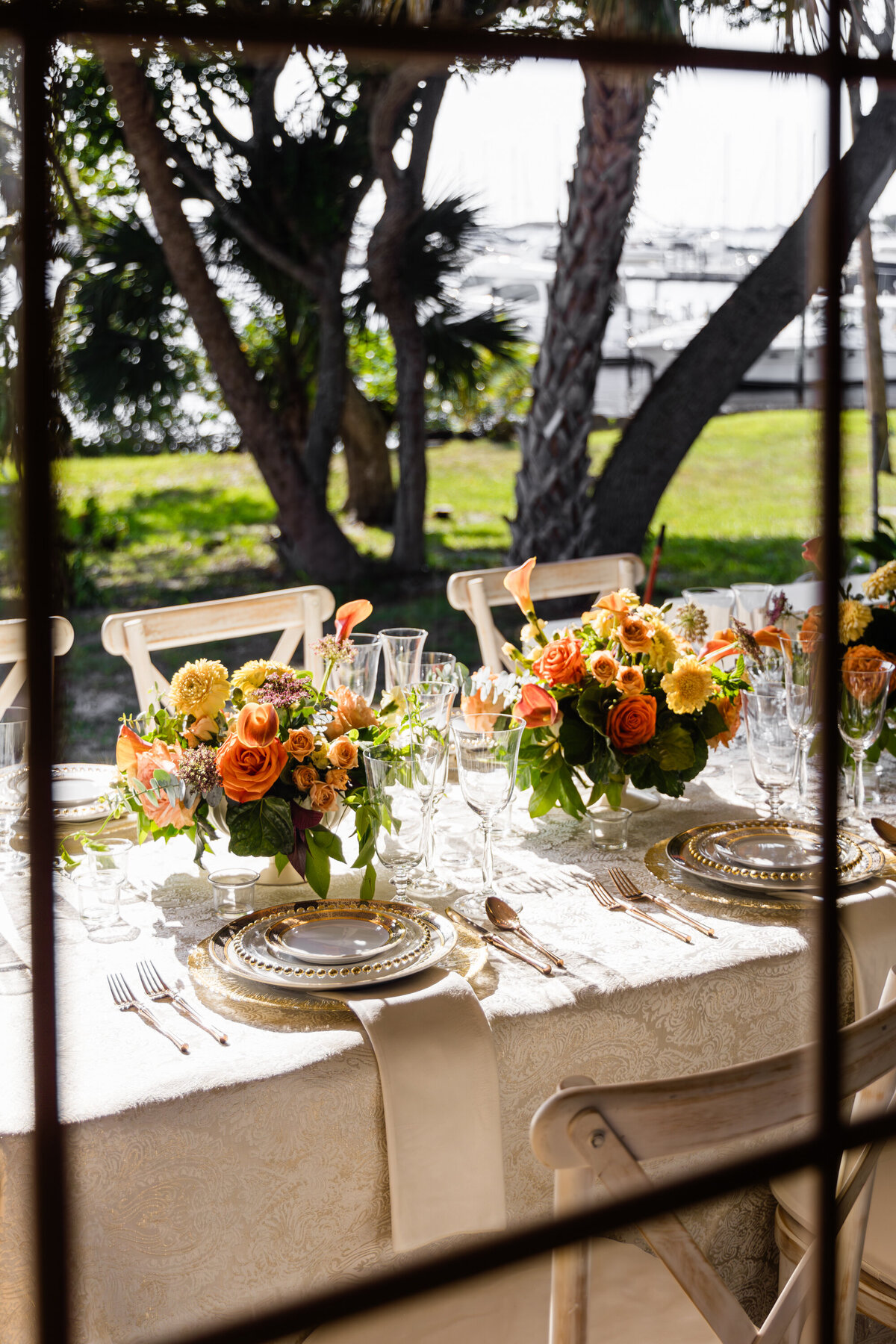 window view of table set with mixed metals place settings drinking glasses overlooking docked yachts in distance