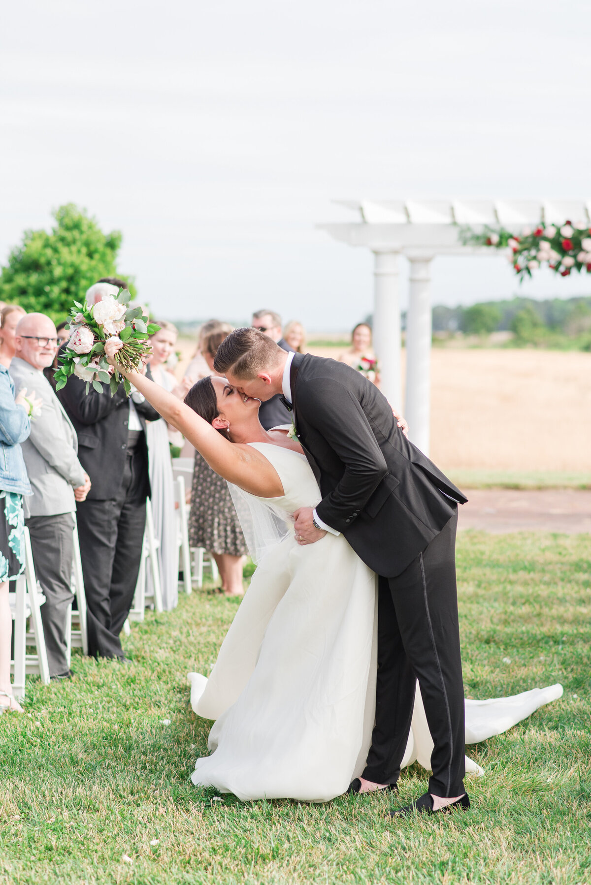 couple kissing qith bouquet in the air after ceremony