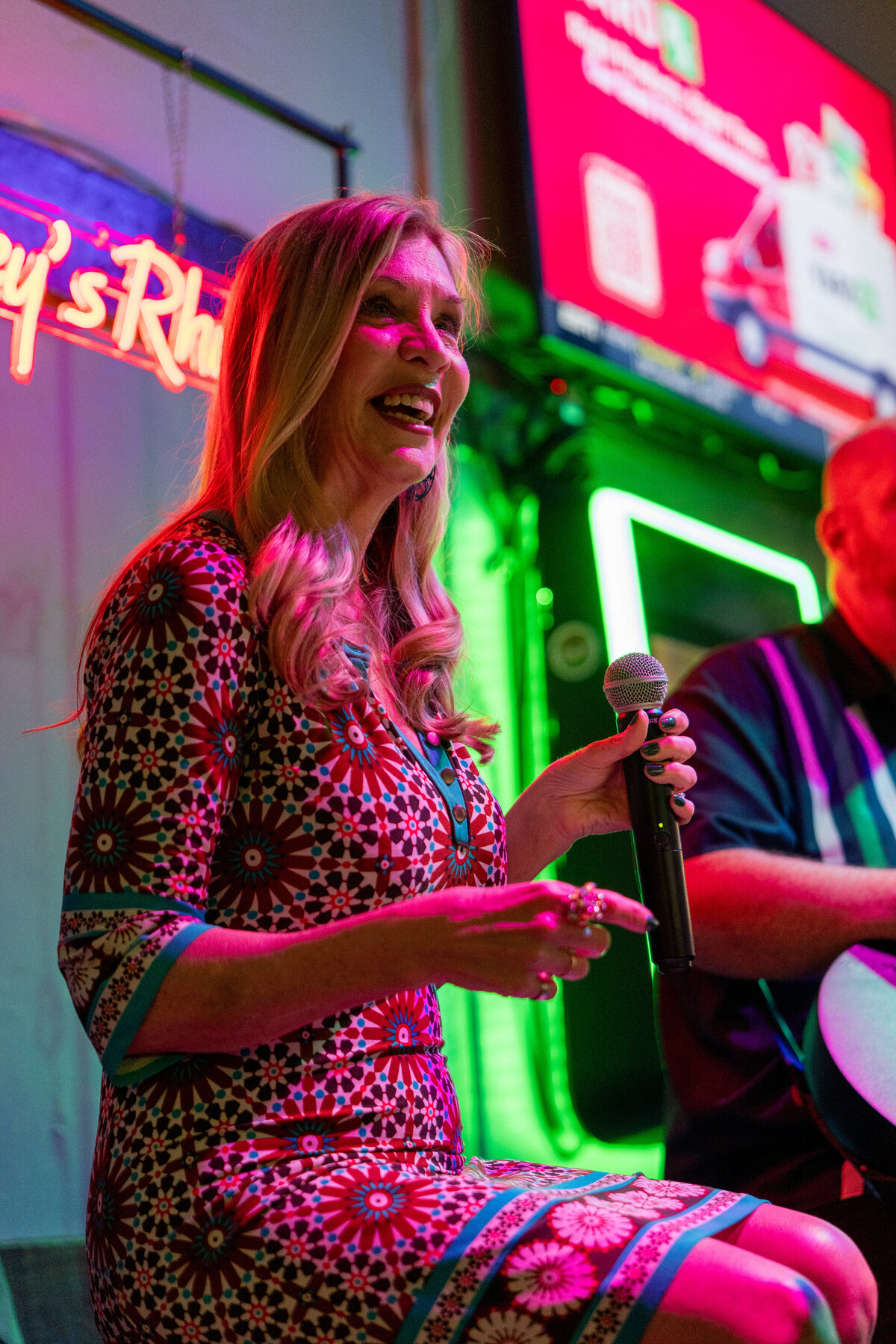 A person smiling while holding a mic